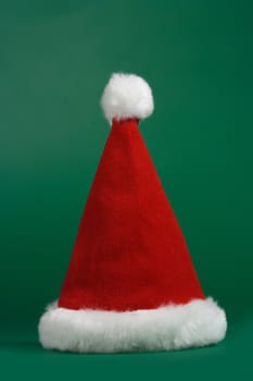 Red and white christmas hat on green background