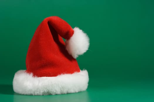 Red and white christmas hat on green background