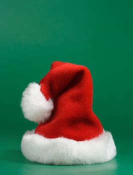 Red and white christmas hat on green background
