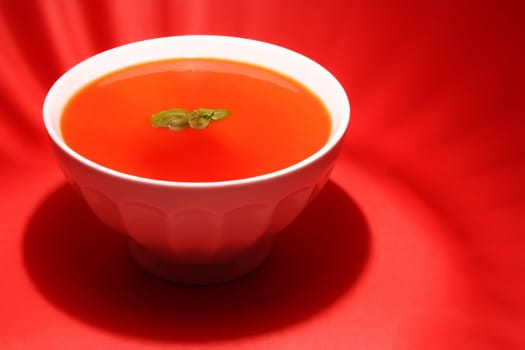 tomato soup in white bowl, red background