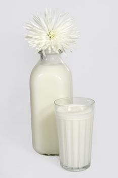 bottle and glass of milk with a white flower