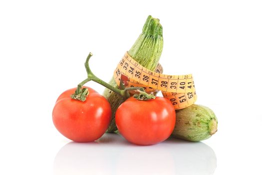 two courgettes and two tomatoes with a tape meter isolated on white background