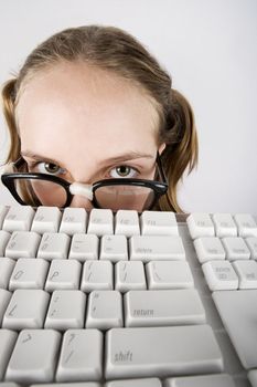 Nerdy Young Girl Peeking Over a Computer Keyboard