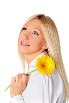  Young smiling blonde in a white shirt plays with a yellow flower in the hands 
