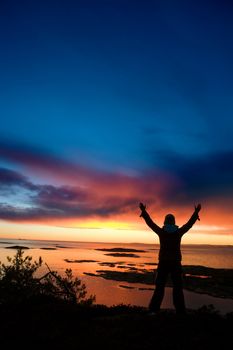 A person standing by the ocean raising their arms in celebration