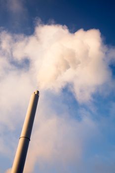 A smoke stack polluting into a blue sky