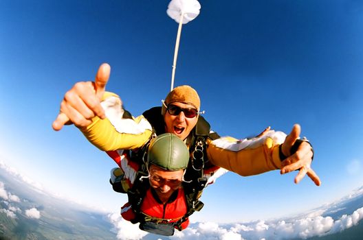 Portrait of two tandem skydivers in action parachuting through the air.