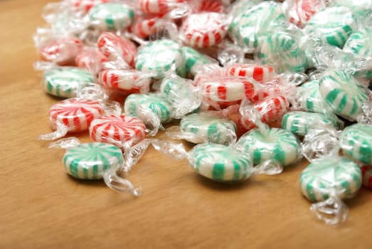 A closeup of peppermint swirl candies on a wooden background.