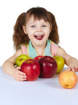 Happy laughing girl with the apples sits at the table