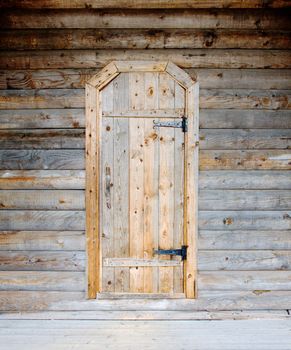 Old-fashioned rural wooden door on a timbered wall
