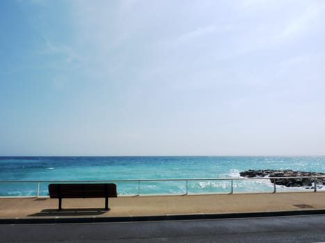 Bench on pavement and mediterranean sea by beautiful weather at Menton, south of France
