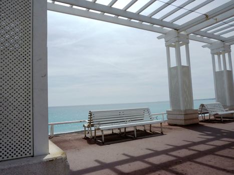 Two white benches and a big white structure in front of mediterranean sea at Nice, France, by beautiful weather