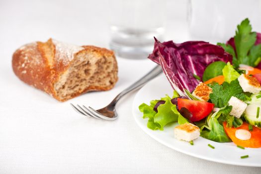 mixed salad on a white plate with a fork