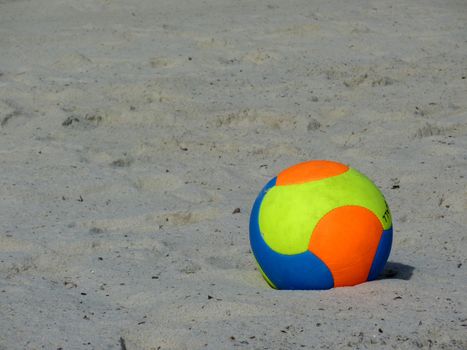 Orange, yellow and blue ball on beach sand
