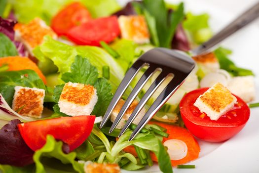 mixed salad on a white plate with a fork