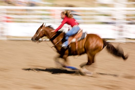 A horse running fast with a female rider - with motion blur.