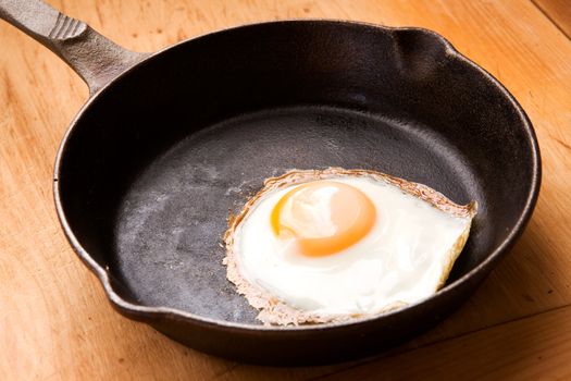 A fried egg in a cast iron frying pan with natural lighting.