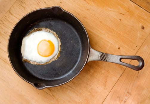 Detail image of a fried egg on a cast iron frying pan viewed from above