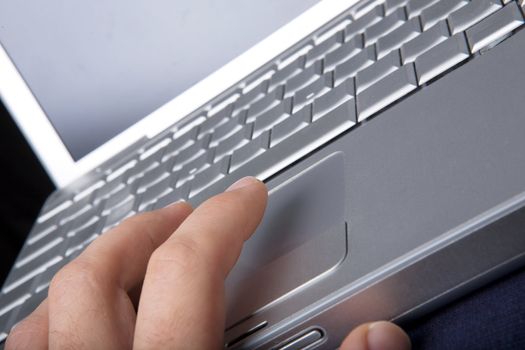 A hand clicking on a one button mouse on a laptop computer - focus on finger