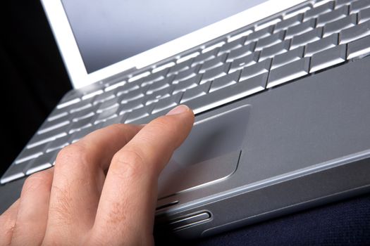 A hand clicking on a one button mouse on a laptop computer - focus on finger