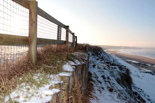 cliff edge fence over a beach on a cold winters day