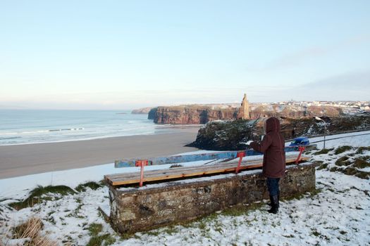 young girl at bench in winter with view of beach and cliffs