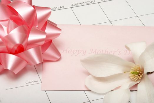 A card for mother lays on a calendar with other accesories for the celebration.