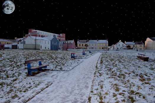 five benches beside a snow covered park footpath under the moonlight