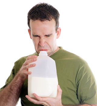 Man smelling a container of milk and discovering it is spoiled, isolated against a white background