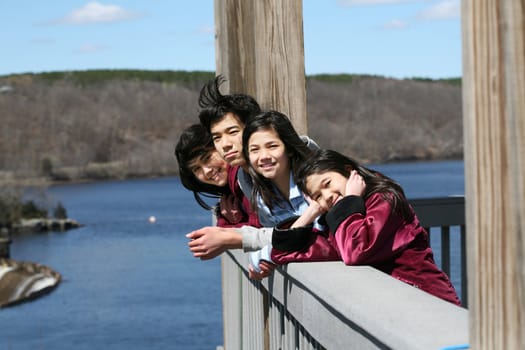 Four children on outdoor deck overlooking river in summer