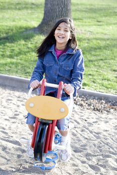 Girl playing on playground rocking horse