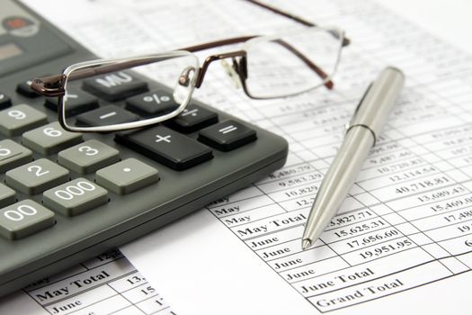 Calculator, modern glasses and pen on financial report