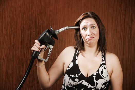 Woman holding gas nozzle like a gun to her head