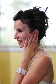 Dark-haired bride holds her hand to her face in surprise, showing her engagement ring.