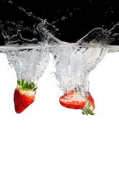 some strawberry pieces thrown in water with black and white background
