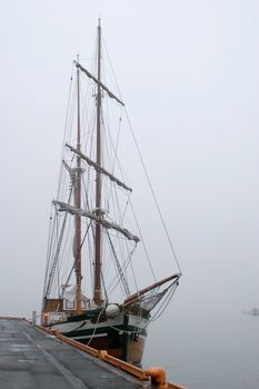 An old wooden sail ship in thick fog.