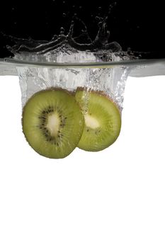 two slices kiwifruit thrown in water with black and white background