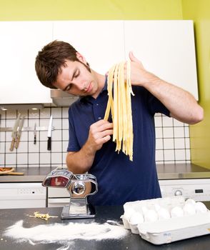 A proud young man with fresh homemade fettuccine looks at the camera- shallow depth of field with focus on the pasta