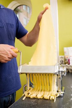 Fettuccine coming out of a manual pastamachine - shallow depth of field with focus on the pasta