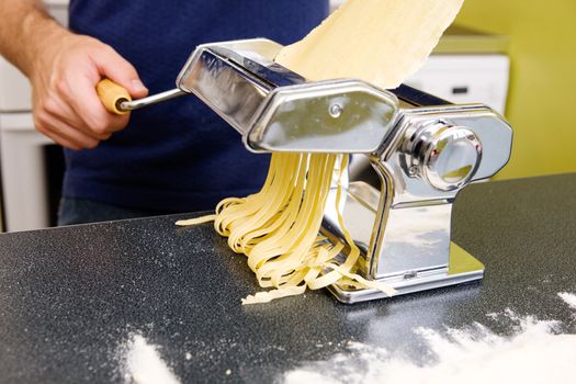 Fettuccine coming out of a manual pastamachine - shallow depth of field with focus on the pasta