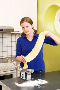 A young woman making pasta in an apartment kitchen.