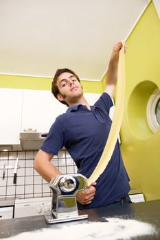 A male proudly showing off his homemade pasta at home in the kitchen