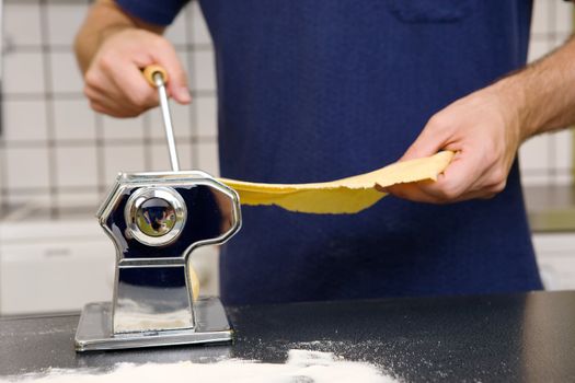 Adjusting the roller on a manual pasta machine - shallow depth of field is used with the focus on the pasta machine