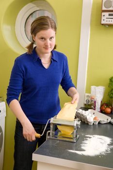 A young woman is making pasta on the counter in her apartment kitchen.  