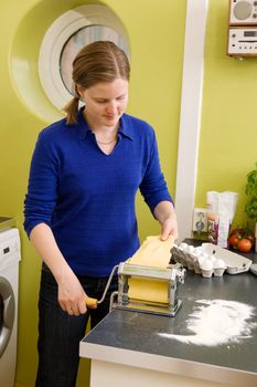 A young woman is making pasta on the counter in her apartment kitchen.  