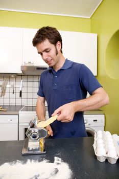 A happy male in the kitchen making pasta by hand