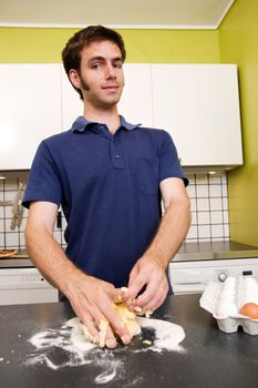 A happy male in the kitchen making pasta by hand and getting messy