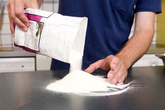 A young man making pasta at home in an apartment kitchen.