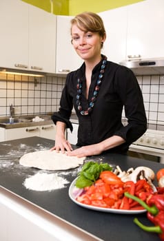 A young woman is making pizza dough on the kitchen counter at home in her apartment. Shallow depth of field with focus on the models face and hands.