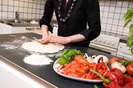 A female making pizza dough at home in the kitchen on the counter.